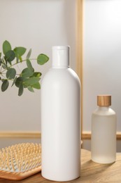 Bottles of shampoo and hairbrush on white table