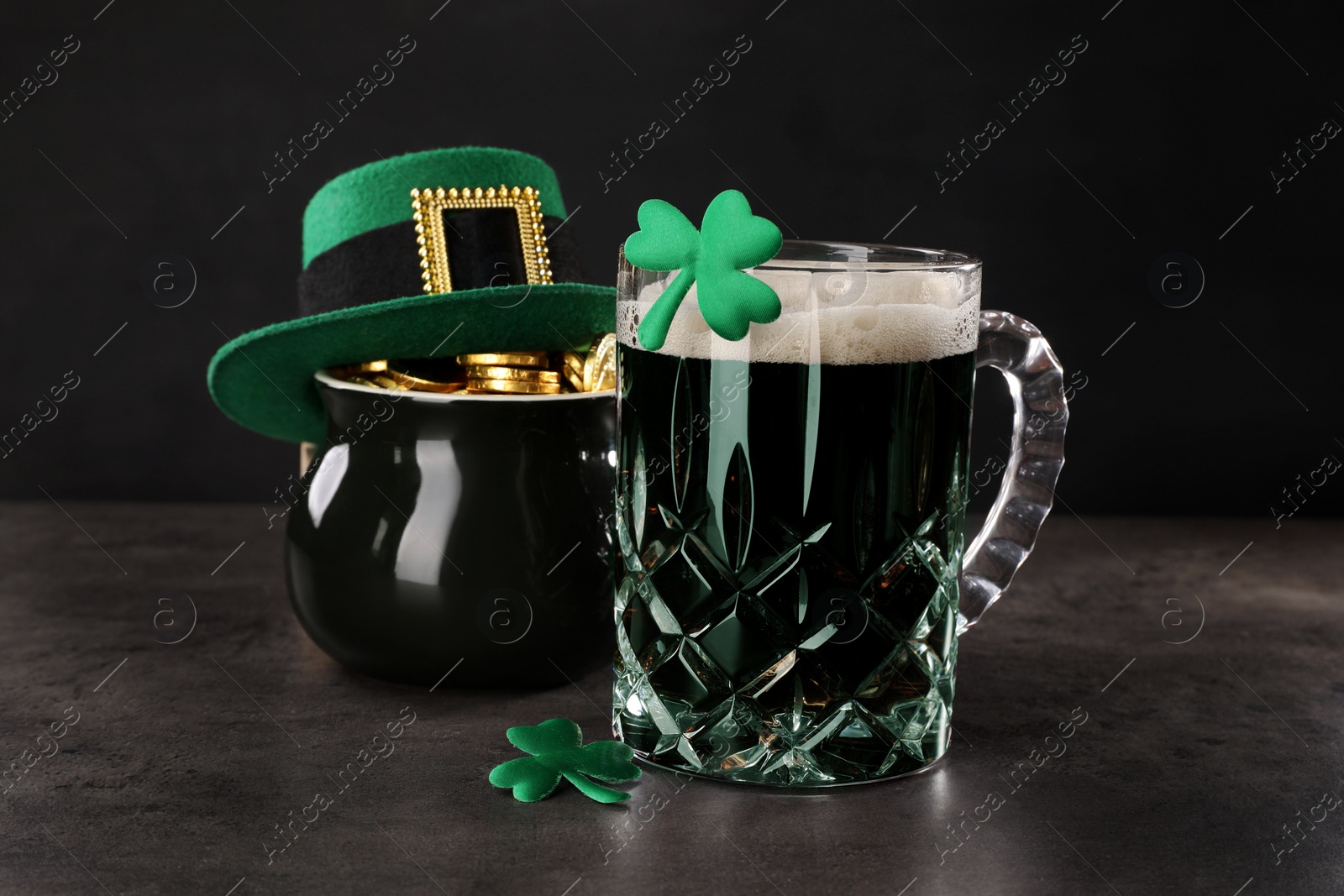 Photo of St. Patrick's day celebration. Green beer, leprechaun hat, pot of gold and decorative clover leaves on grey table