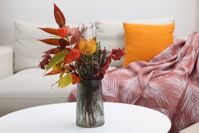 Vase with bouquet of dry flowers and leaves on side table in living room