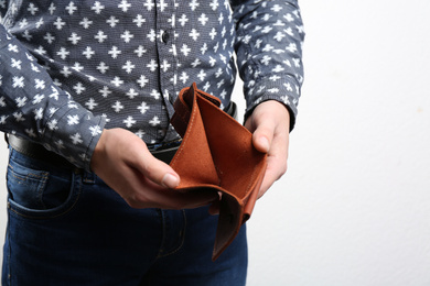 Photo of Man showing empty wallet on light background, closeup