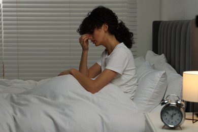 Photo of Young woman suffering from headache in bed at night