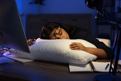 Tired overworked businesswoman napping with pillow at night in office