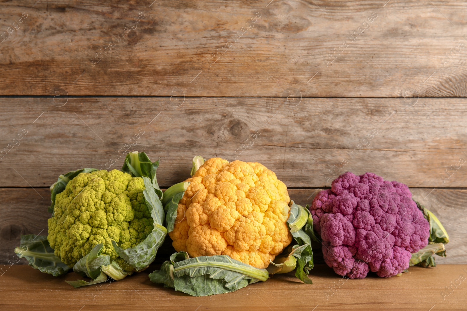 Photo of Colorful cauliflower cabbages on wooden table. Healthy food