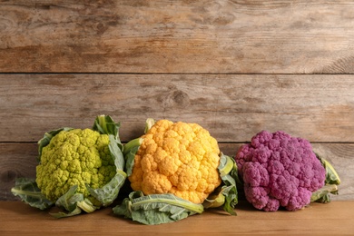 Photo of Colorful cauliflower cabbages on wooden table. Healthy food