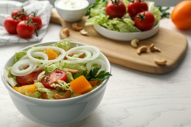 Bowl of delicious salad with Chinese cabbage, tomatoes and onion on white wooden table, closeup. Space for text