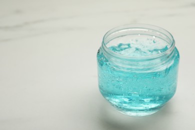 Photo of Jar of blue cosmetic gel on light background, space for text