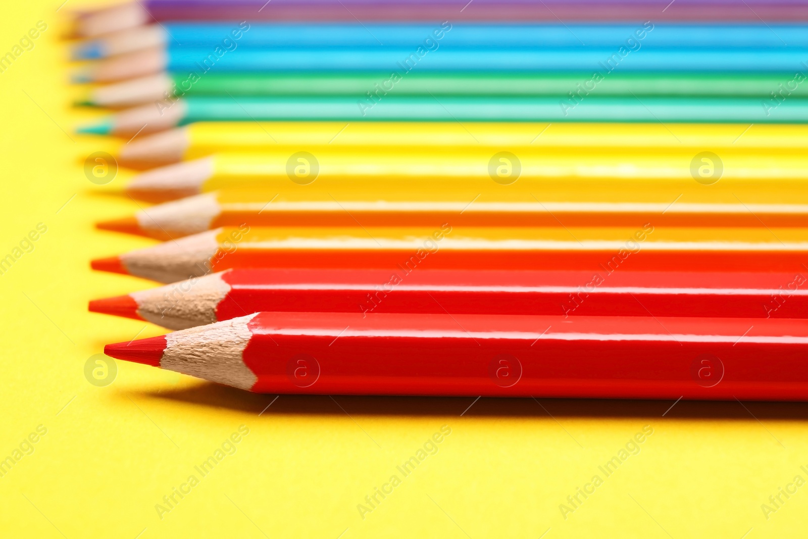 Photo of Different color pencils on yellow background, closeup