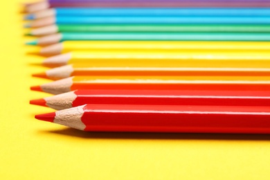 Photo of Different color pencils on yellow background, closeup