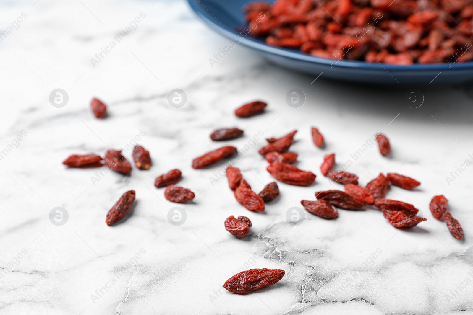 Photo of Dried goji berries on white marble table, closeup