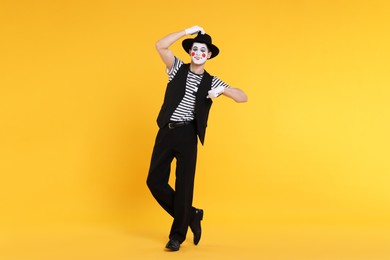 Photo of Funny mime artist in hat posing on orange background