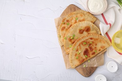 Photo of Delicious fried chebureki with cheese and green onion on white textured table, flat lay. Space for text