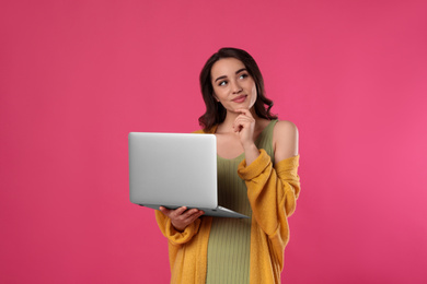 Photo of Pensive young woman with laptop on pink background
