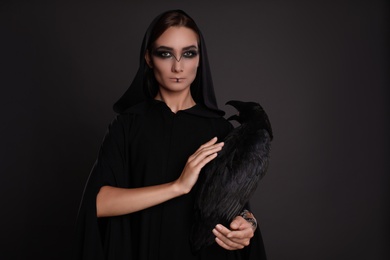 Mysterious witch with raven on black background