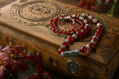 Photo of Beautiful necklace with gemstones, flowers and wooden jewelry box on table