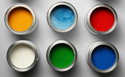 Photo of Open paint cans on grey background, top view