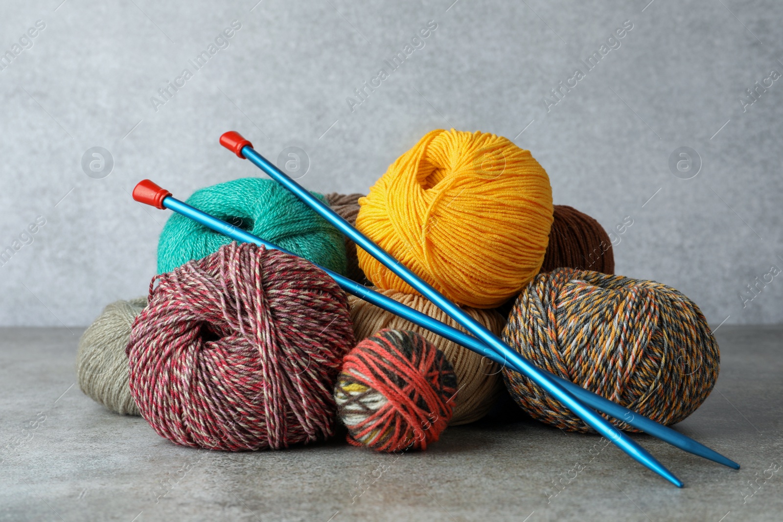 Photo of Soft woolen yarns and knitting needles on grey table