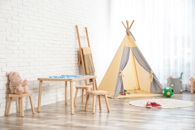 Cozy kids room interior with table, stools and play tent