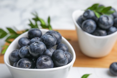 Bowl of tasty fresh blueberries on board, closeup. Space for text