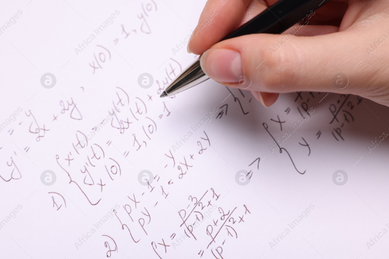 Photo of Student writing different mathematical formulas on paper, closeup