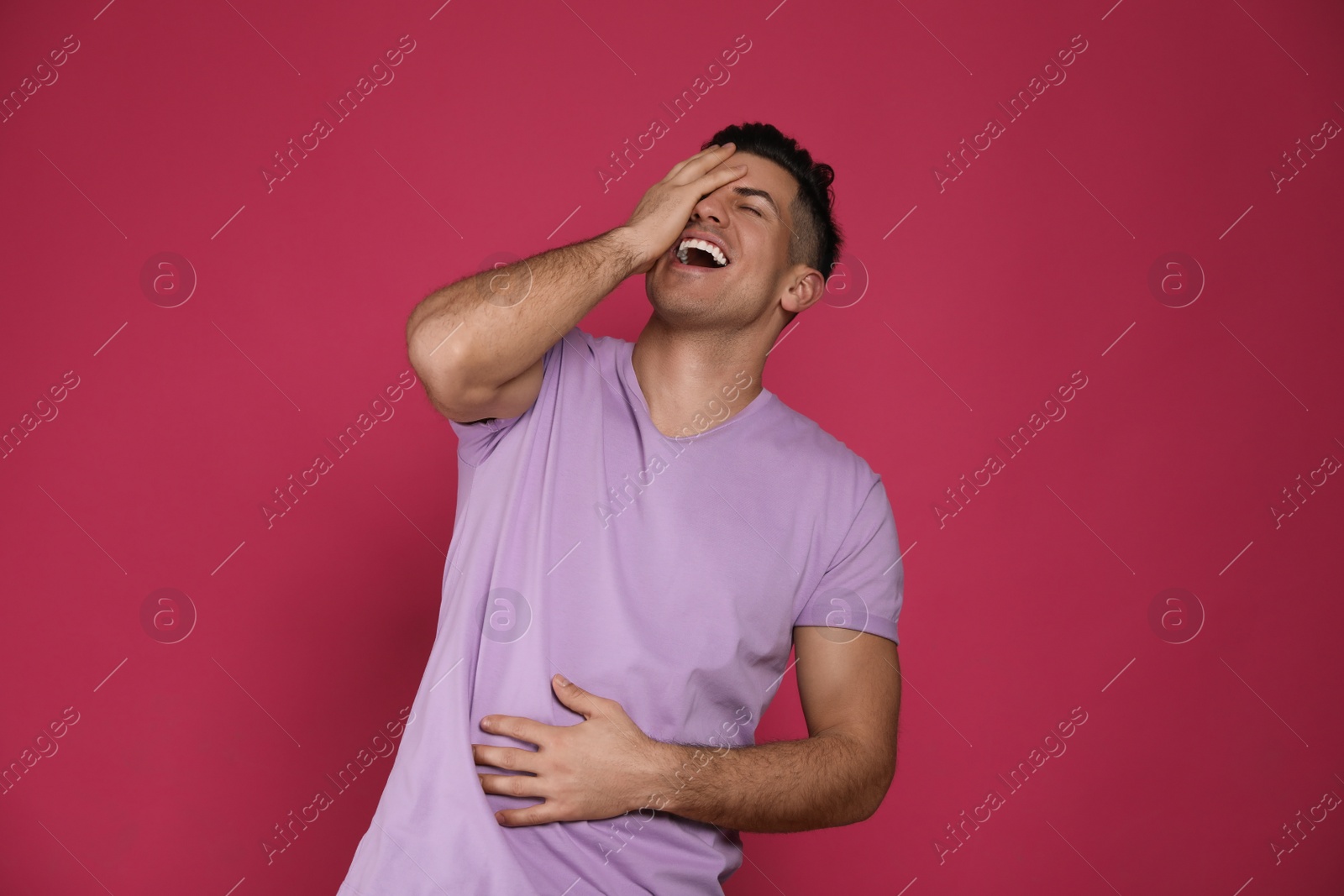 Photo of Handsome man laughing on maroon background. Funny joke