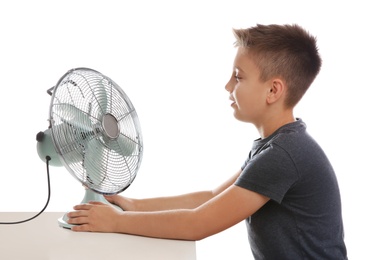 Photo of Little boy enjoying air flow from fan on white background. Summer heat