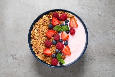 Photo of Tasty homemade granola with yogurt on grey table, top view. Healthy breakfast