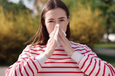 Photo of Woman with napkin suffering from seasonal allergy outdoors