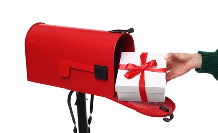 Photo of Woman putting Christmas gift into mailbox on white background, closeup. Sending present by mail