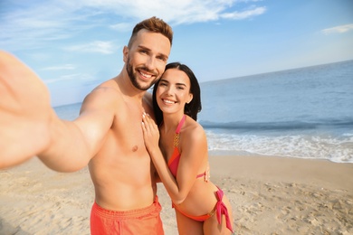 Photo of Happy young couple taking selfie on beach