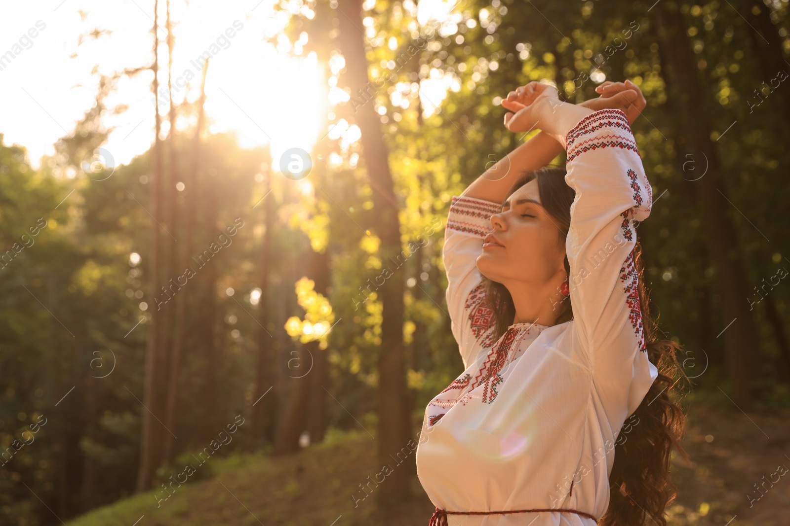 Photo of Beautiful woman in embroidered shirt outdoors on sunny day, space for text. Ukrainian national clothes