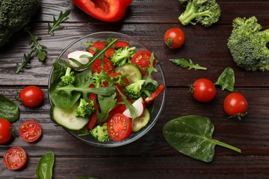 Photo of Tasty fresh vegetarian salad on dark wooden table, flat lay