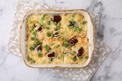 Photo of Tasty sausage casserole in baking dish on white marble table, top view