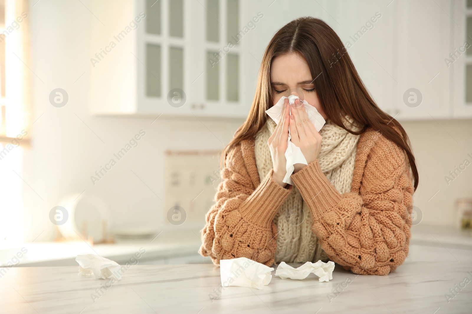 Photo of Sick young woman sneezing in kitchen. Influenza virus