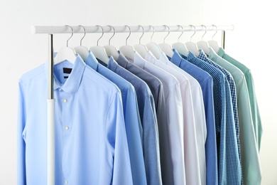 Photo of Men's clothes hanging on wardrobe rack against white background