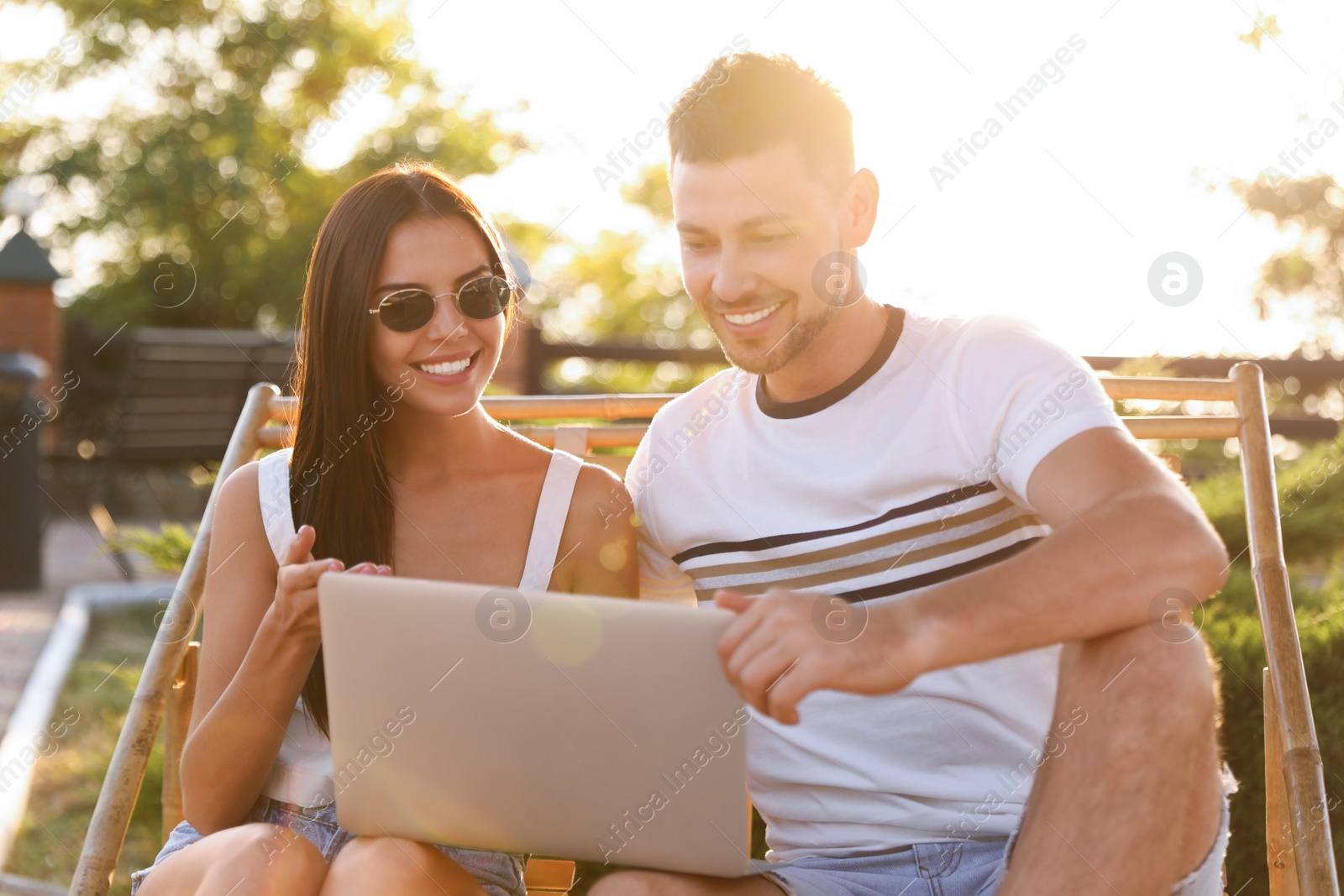 Image of Happy couple with laptop resting together outdoors