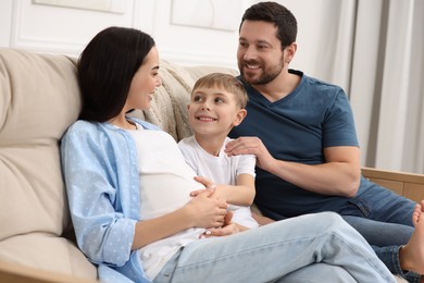 Photo of Pregnant woman spending time with her son and husband at home. Happy family