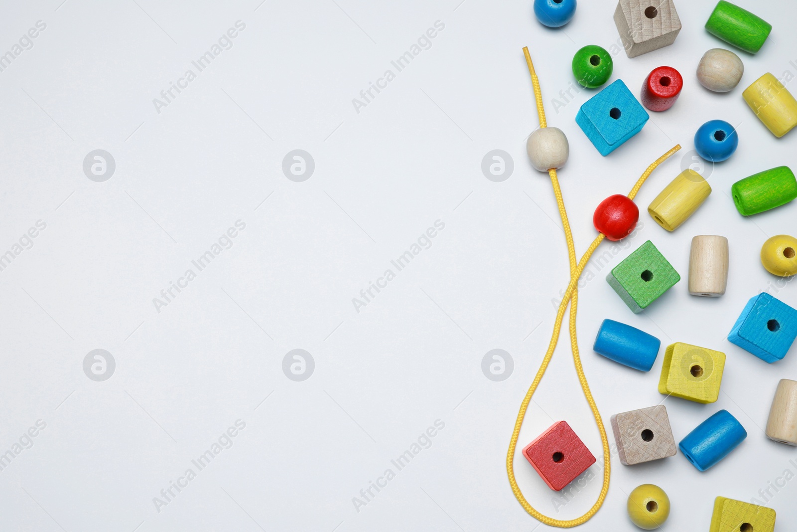 Photo of Wooden pieces and string for threading activity isolated on white, top view. Educational toy for motor skills development