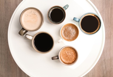 Many cups of different aromatic hot coffee on table, top view