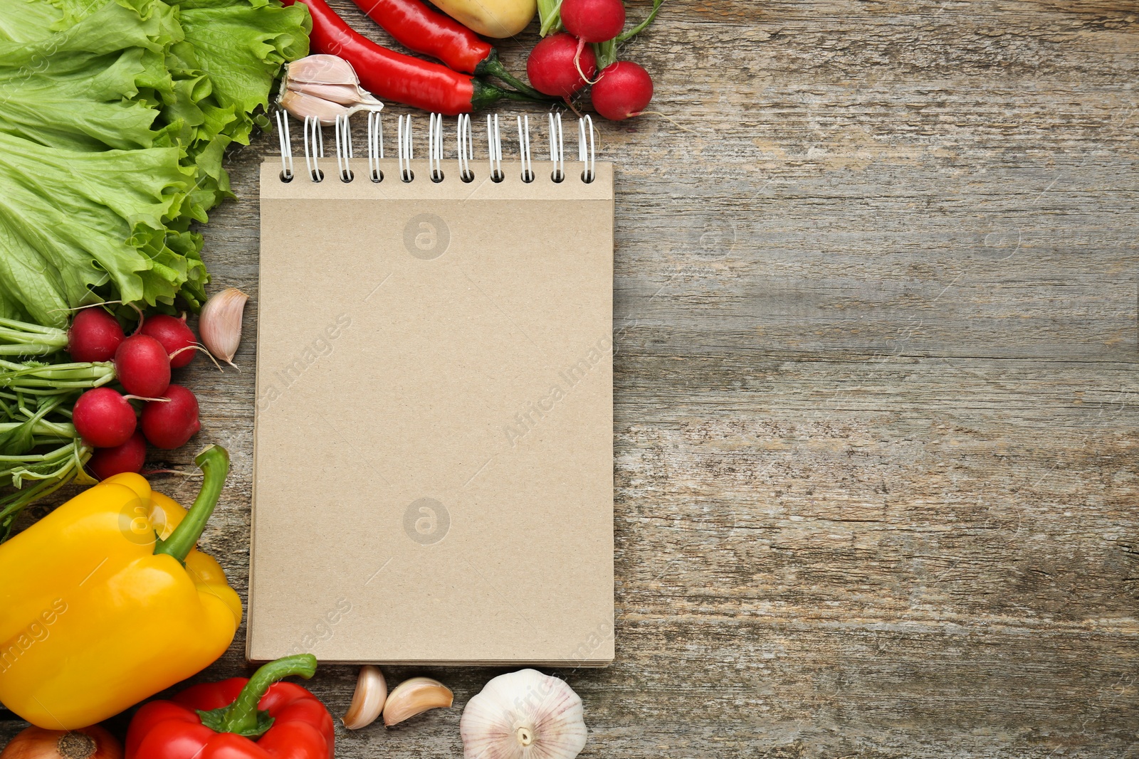 Photo of Blank recipe book and different ingredients on wooden table, flat lay. Space for text