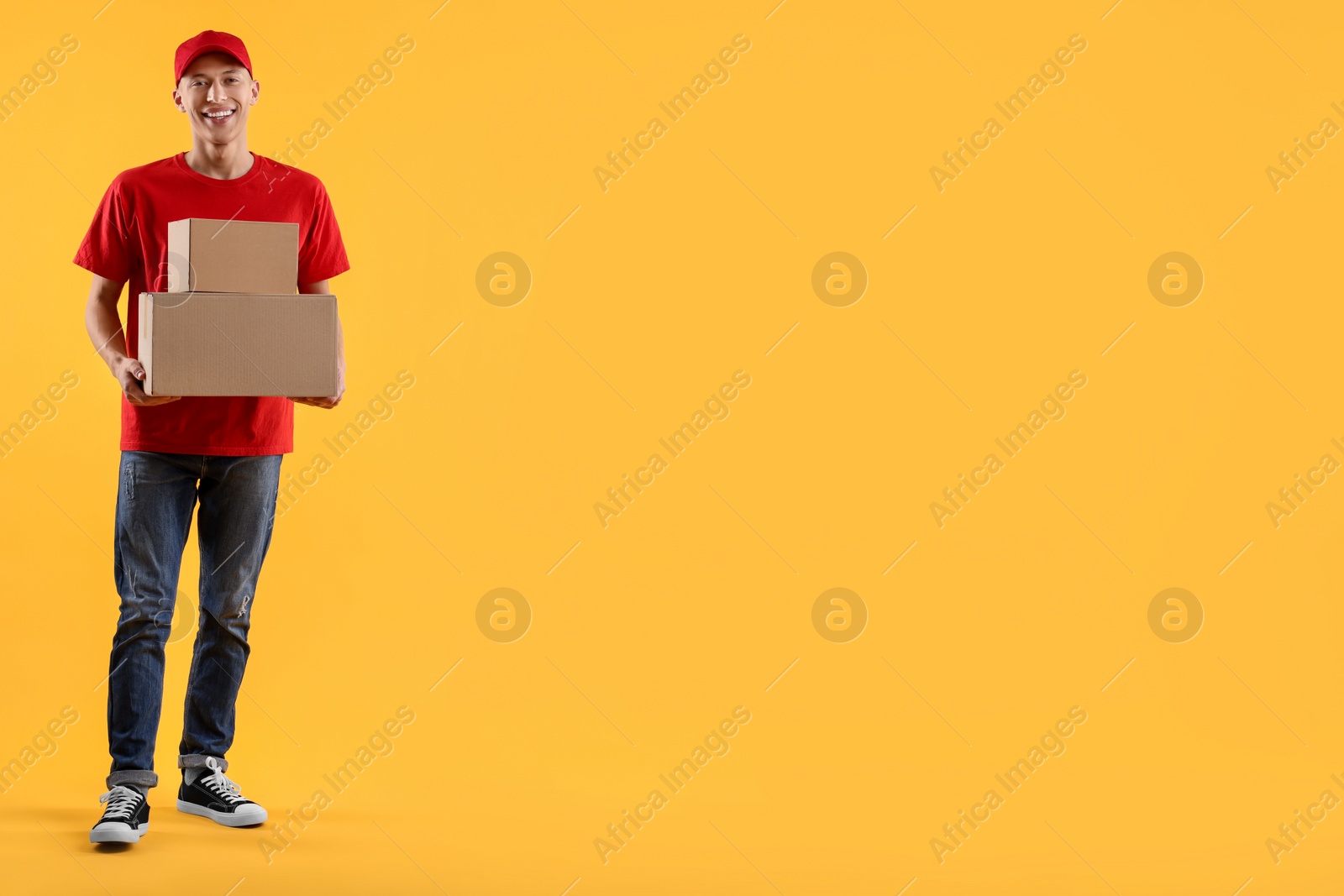 Photo of Happy courier with parcels on yellow background. Space for text