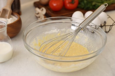 Metal whisk, cream in bowl and different products on light table