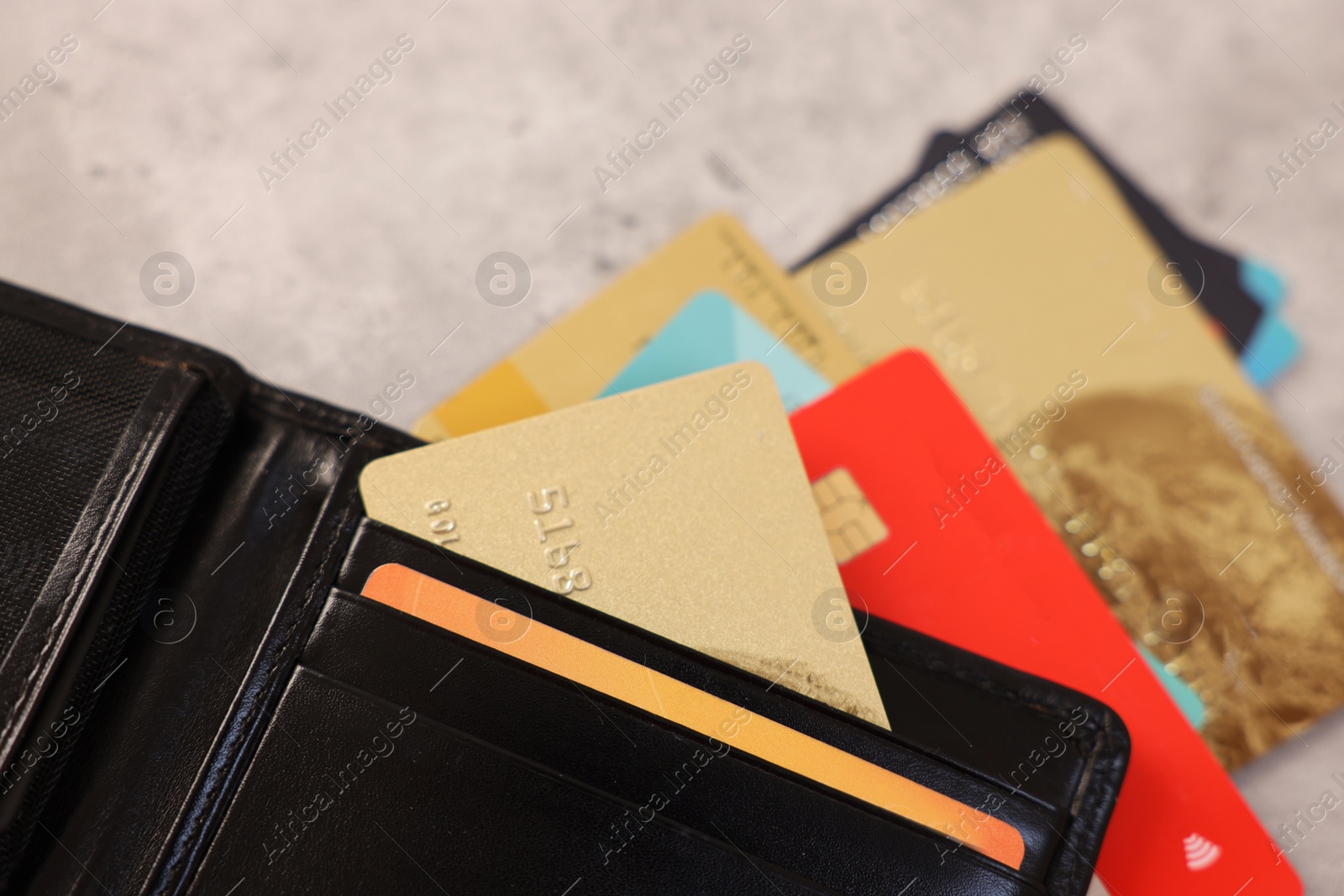 Photo of Many different credit cards and leather wallet on grey table, closeup