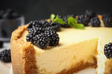 Photo of Delicious cheesecake decorated with blackberries on table