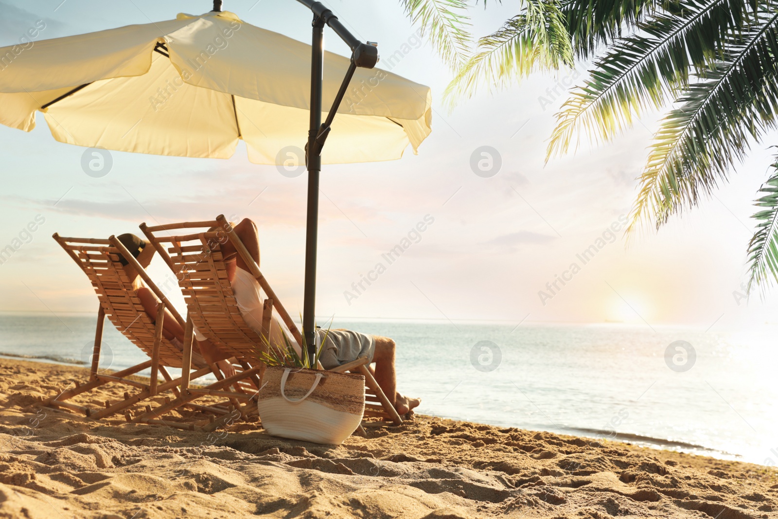 Image of Couple enjoying their summer vacation on sandy beach at sunset