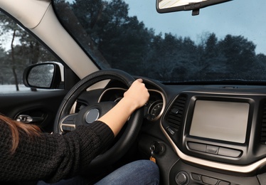 Photo of Young woman driving car along winter forest, closeup