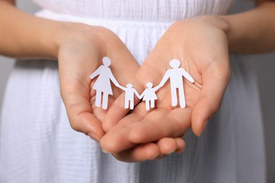 Photo of Woman holding paper family figures, closeup. Insurance concept