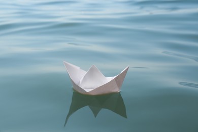 Photo of White paper boat floating on water surface