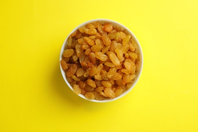 Bowl with raisins on color background, top view. Dried fruit as healthy snack