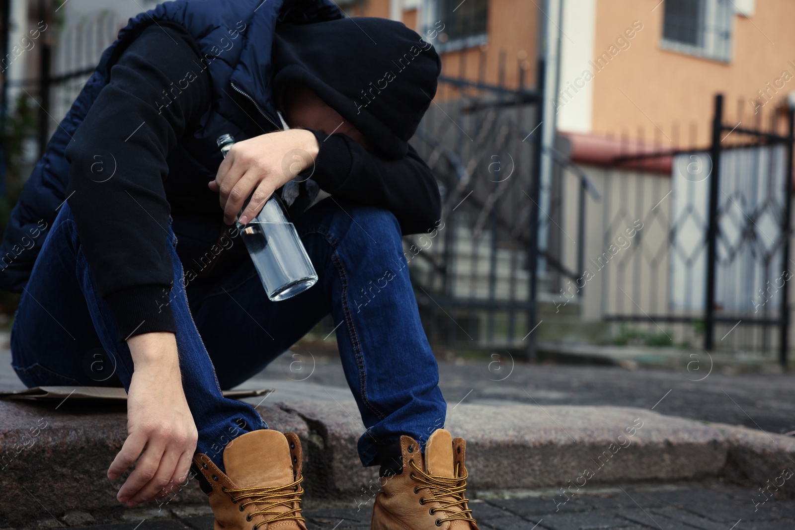 Photo of Addicted drunk man with alcoholic drink on stairs outdoors