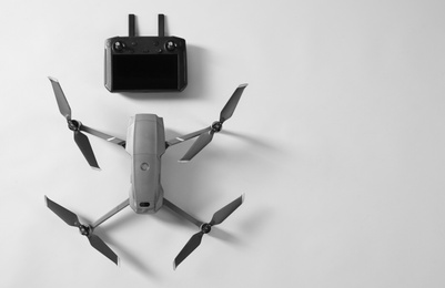 Photo of Modern drone with controller on light background, top view. Space for text